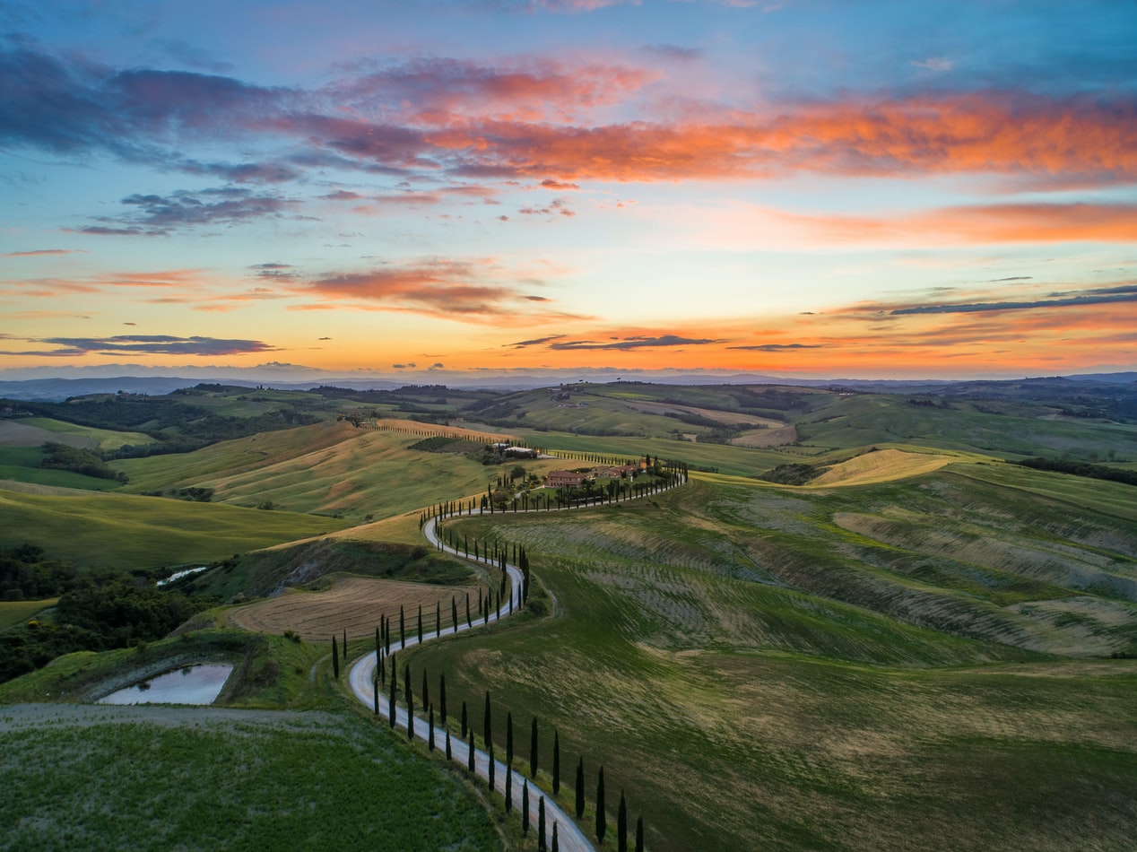 road between green grass field near mountains under blue and brown sky at golden hour photo – Free Italy Image on Unsplash